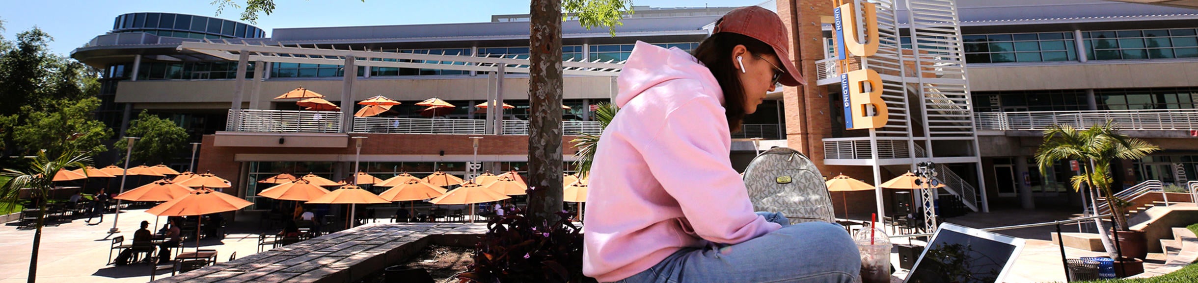 A female student works on her laptop in HUB Plaza.